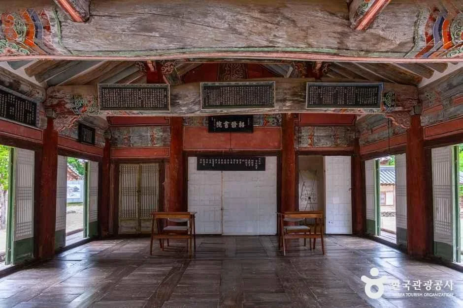 Wooden floorboards, red columns, exposed beams and hanging plaques inside the lecture building at Sosu Seowon